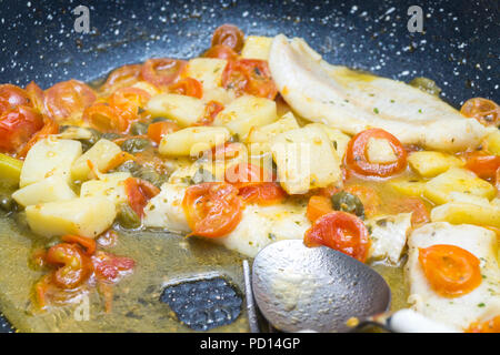 Cabillaud cuit dans une casserole, avec de la tomate, les pommes de terre et les câpres Banque D'Images