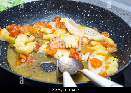 Cabillaud cuit dans une casserole, avec de la tomate, les pommes de terre et les câpres Banque D'Images