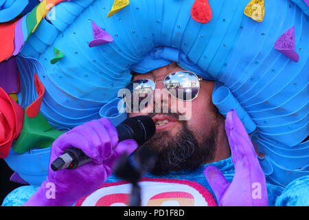 Reflectoions des lunettes de soleil de la grande robe rose homme joue sur la scène à la place du millénaire à Londres pour l'événement de la fierté LGBT Banque D'Images