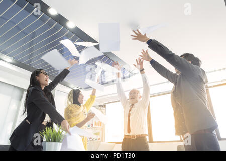 Les gens d'affaires d'équipe jeter Papiers et documents, voler dans l'air alors que heureux sourire heureux. Concept de l'équipe de succès après avoir signer un contrat ou terminé la Banque D'Images