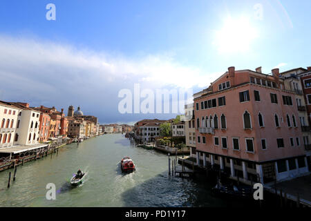 Transport de personnes et de marchandises des bateaux sur le Grand Canal, Venise, Italie, tandis que le soleil éclaire les façades basse au nord du canal Banque D'Images