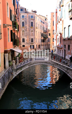Petite passerelle romantique, d'un canal étroit entouré de jolies maisons aux façades rose à Venise, Italie Banque D'Images