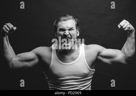 Photo en noir et blanc. En colère sportsman montrant son musculars. vigueur concept. puissance physique Banque D'Images