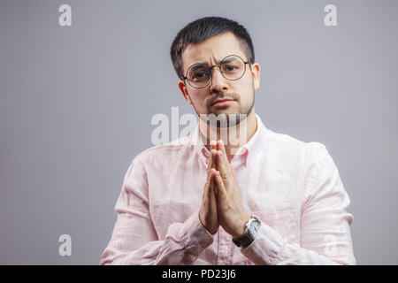 Portrait de l'homme agréable à prier pour la santé et d'affaires. isolé sur fond gris. S'il vous plaît, donnez-moi le travail. Je vous promets que je ne vais pas le faire encore une fois Banque D'Images