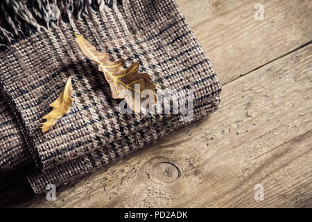 De l'automne. Brown plaid à carreaux avec des feuilles sèches sur fond de bois. Banque D'Images