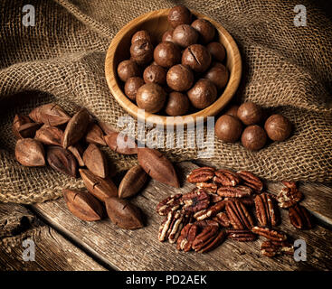 Macadamia, pacanes et noix de pili sur table en bois. Banque D'Images