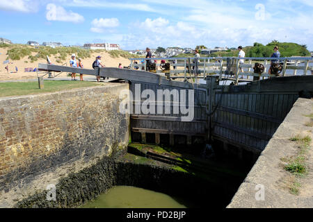 Bude, Cornwall, UK. Les vacanciers profiter du temps chaud en marchant le long du canal de Bude et la traversée de la mer lock Banque D'Images