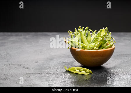 Photo de gousses de pois verts dans la plaque en bois sur le tableau noir en blanc avec pod Banque D'Images