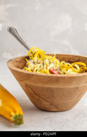 Courgettes végétalien premières nouilles au tofu et les tomates dans un bol en bois. Concept alimentaire végétalien premières en bonne santé. Banque D'Images