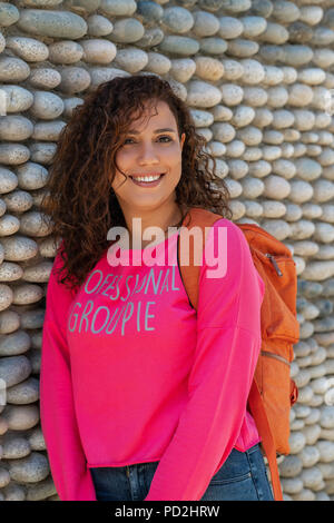 Close up portrait of a cheerful curly young university student woman smiling outdoors. Banque D'Images