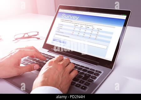 Close-up of a Businessman's Hand remplissant le formulaire de sondage en ligne sur l'ordinateur portable Banque D'Images