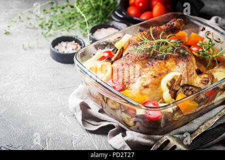 Poulet entier cuit au four avec légumes et herbes close-up sur une plaque sur une table. Banque D'Images
