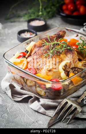 Poulet entier cuit au four avec légumes et herbes close-up sur une plaque sur une table. Banque D'Images