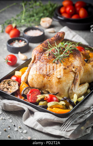 Poulet entier cuit au four avec légumes et herbes close-up sur une plaque sur une table. Banque D'Images