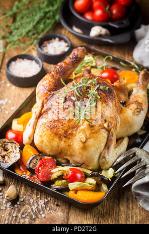 Poulet entier cuit au four avec légumes et herbes close-up sur une plaque sur une table. Banque D'Images