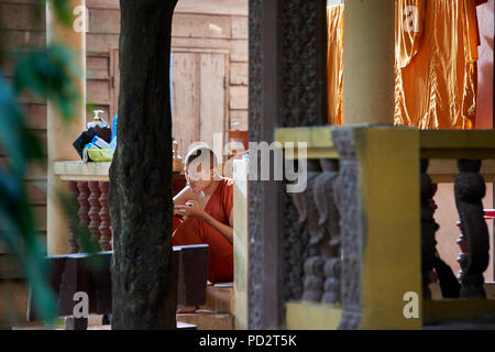 Un jeune moine bouddhiste se détend au soleil près de ses robes de séchage. À Siem Reap, Cambodge. Banque D'Images