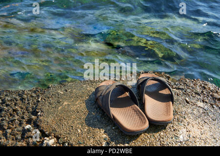 Une paire de sandales en cuir pour hommes à bord de l'eau par la mer Banque D'Images