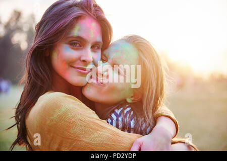 Deux jeunes femmes aux visages recouverts de poudre de craie de couleur hugging at Festival Holi, portrait Banque D'Images