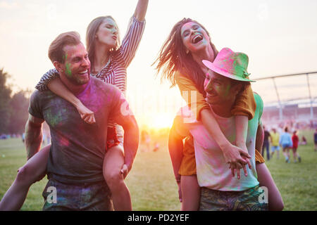 Deux jeunes couples couvert de poudre de craie de couleur sur le dos au Festival Holi Banque D'Images