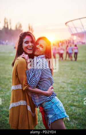 Deux jeunes femmes couvertes de poudre de craie de couleur en serrant au Festival Holi, portrait Banque D'Images