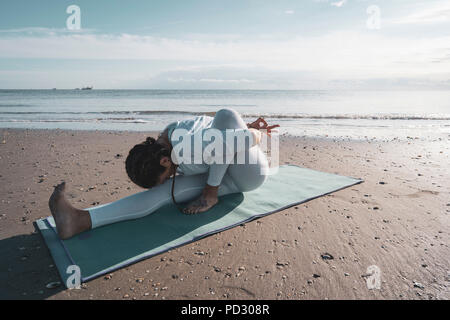 Woman practicing yoga on beach Banque D'Images