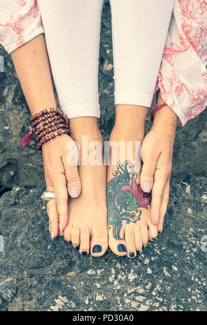 Femme tatouée de toucher les pieds avec les mains Banque D'Images