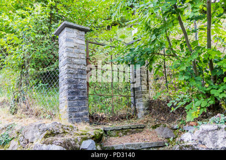 Rusty Old vintage ornate gates entre des murs en pierre dans une forêt, abandonnés, ruines, la Suisse, l'Europe porte en fer forgé Banque D'Images