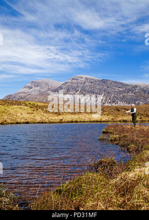 La pêche du pêcheur à la truite brune sauvage sur la colline à distance sur le loch Domaine forestier Reay, Arkle en arrière-plan, Sutherland, Highlands, Scotland UK. Banque D'Images