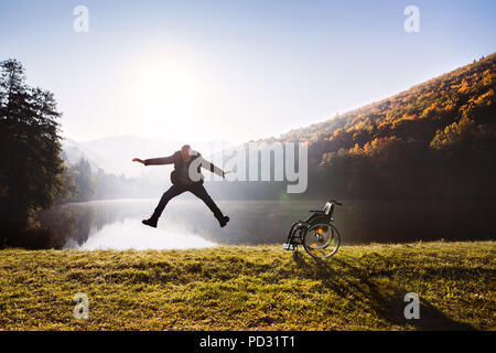 Man jumping par le fauteuil roulant à l'automne la nature. Banque D'Images