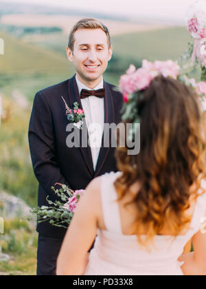 Le marié est souriant pour la mariée placés dans l'avant de lui. Banque D'Images