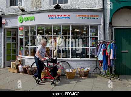 Senior woman hors magasin de charité Oxfam, England UK Banque D'Images