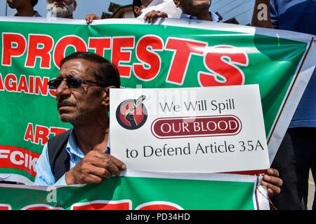 5 août 2018 - Srinagar, J&K, Inde - un membre du Cachemire Traders et fabrique de Russie (KTMF) vu holding a placard pendant la manifestation.La vie dans la vallée du Cachemire s'est interrompue en raison d'un arrêt complet appelé par le leadership de la résistance conjointe (JRL) contre le défi juridique à la Cour suprême sur la validité de l'article 35-A, qui interdit les gens de l'extérieur de Jammu-et-Cachemire de l'acquisition de biens immeubles dans l'état. Traders ont organisé un sit-down à l'horloge de la tour historique de Lal Chowk pour protester contre l'assaut juridique ''' sur l'article 35-A. Les manifestants portant des pancartes Banque D'Images