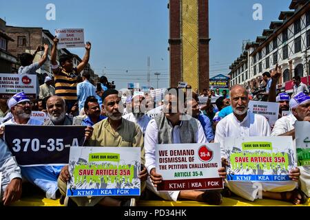 5 août 2018 - Srinagar, J&K, l'Inde - Membres du Cachemire Traders et fabrique de Russie (KTMF) vu la tenue des pancartes pendant la manifestation.La vie dans la vallée du Cachemire s'est interrompue en raison d'un arrêt complet appelé par le leadership de la résistance conjointe (JRL) contre le défi juridique à la Cour suprême sur la validité de l'article 35-A, qui interdit les gens de l'extérieur de Jammu-et-Cachemire de l'acquisition de biens immeubles dans l'état. Traders ont organisé un sit-down à l'horloge de la tour historique de Lal Chowk pour protester contre l'assaut juridique ''' sur l'article 35-A. Les manifestants portant des pancartes sh Banque D'Images