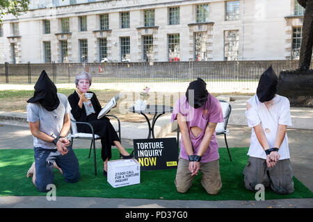 London UK, 6 août 2018. Amnesty International UK stunt. Militant à Theresa peut masquer est montré trois ignorant la torture 'victimes' dans stunt mettant en lumière l'appel des militants pour l'enquête sur la participation britannique à la torture. Immédiatement après le stunt, Amnistie, grâce, à la liberté et à l'abri de la torture a remis une pétition, forte de 27 000 à 10 Downing Street avec un appel officiel de la torture une enquête.C opyright Carol Moir/AlamyLiveNews Banque D'Images