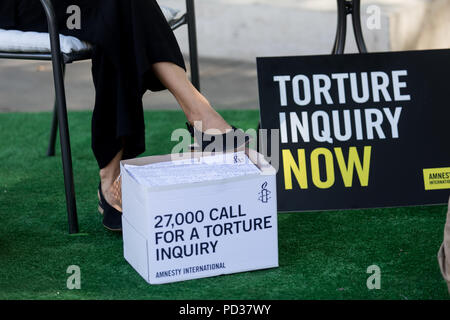 London UK, 6 août 2018. Amnesty International UK stunt. Militant à Theresa peut masquer est montré trois ignorant la torture 'victimes' dans stunt mettant en lumière l'appel des militants pour l'enquête sur la participation britannique à la torture. Immédiatement après le stunt, Amnistie, grâce, à la liberté et à l'abri de la torture a remis une pétition, forte de 27 000 à 10 Downing Street avec un appel officiel de la torture une enquête.C opyright Carol Moir/AlamyLiveNews Banque D'Images