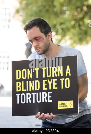 London UK, 6 août 2018. Amnesty International UK stunt. Militant à Theresa peut masquer est montré trois ignorant la torture 'victimes' dans stunt mettant en lumière l'appel des militants pour l'enquête sur la participation britannique à la torture. Immédiatement après le stunt, Amnistie, grâce, à la liberté et à l'abri de la torture a remis une pétition, forte de 27 000 à 10 Downing Street avec un appel officiel de la torture une enquête.C opyright Carol Moir/AlamyLiveNews Banque D'Images