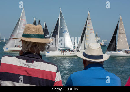 Cowes, UK. 6 août 2018. Le haut tempertatures continuent et les gens à faire les la plupart des sex suuny météo à la semaine de Cowes sur l'île de Wight. Deux hommes portant des chapeaux d'été regarder yacht racing à la semaine de Cowes sur l'île de Wight les gens au soleil à regarder le yacht à courses et passer du temps ensemble sur la plage, dans le chaud soleil d'août. Crédit : Steve Hawkins Photography/Alamy Live News Banque D'Images