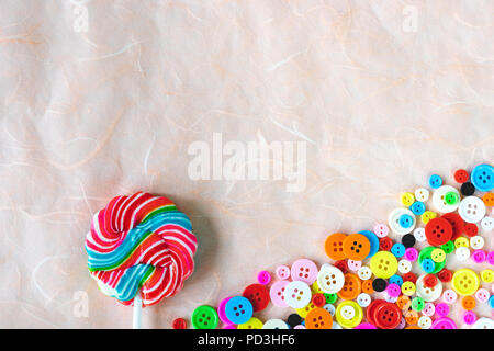 Les boutons colorés et lollipop swirl sur papier mûrier rose Banque D'Images