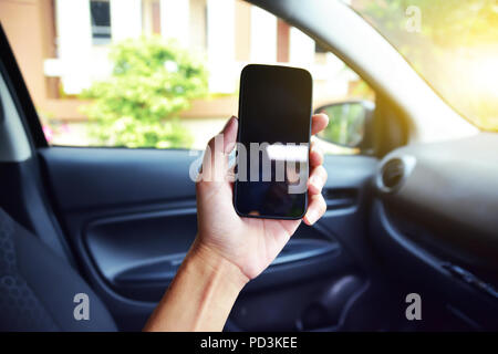 Hand holding smartphone en voiture en stationnement sur rue.Et l'utilisation de smartphone pour les achats en ligne par internet Banque D'Images