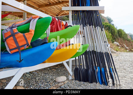 Kayaks, gilets, avirons sous un toit de bois sur la plage. Banque D'Images