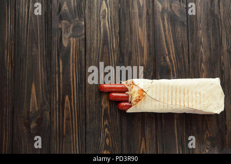 Saucisse fumée dans le pain pita sur un fond de bois foncé.photo w Banque D'Images