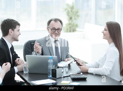 Discuter de questions liées au travail Manager avec ses assistants derrière un bureau Banque D'Images