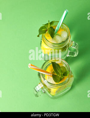 Vue de dessus de pots de verre avec de la limonade faite maison à partir d'ingrédients naturels sur un fond vert. Banque D'Images