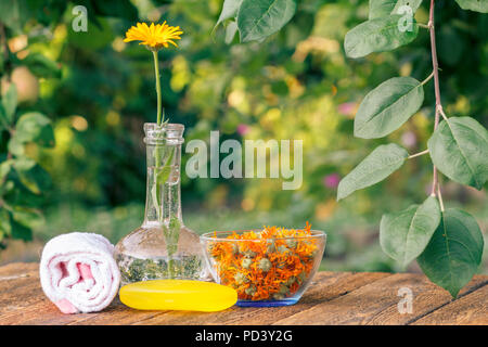 Produits Spa et accessoires. Serviette, savon à l'extrait de souci, calendula fleurs dans un flacon en verre et bol avec des fleurs sèches de calendula sur b en bois Banque D'Images