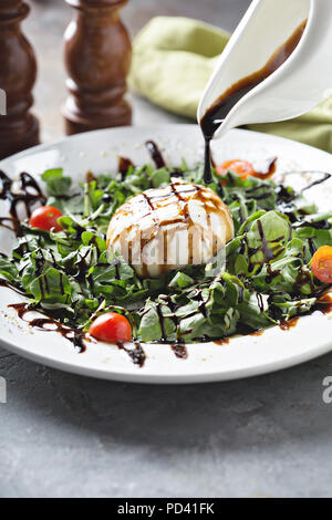 Burrata et salade de roquette au vinaigre balsamique sur glaçure Banque D'Images