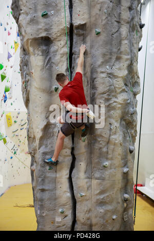 Photo de retour de l'homme grimpant boulder en salle de sport Banque D'Images