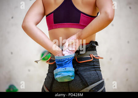 Photo de l'arrière de l'athlète féminin avec sac de talc contre mur de fond pour l'escalade Banque D'Images