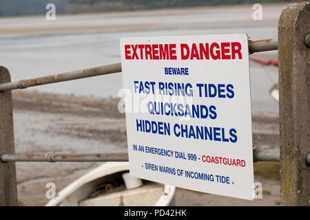 Un signe d'avertissement des dangers de marées, des sables mouvants et chaînes masquées sur le front de mer du village de Arnside dans Cumbria en regard de l'estuaire de Kent. C Banque D'Images