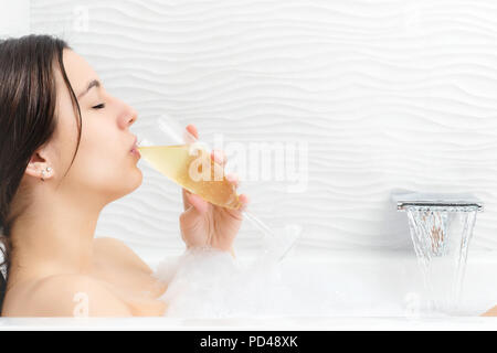 Close up portrait of young woman drinking champagne bain de mousse. Banque D'Images