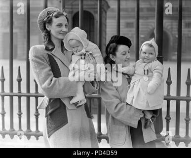 26 mars, 1945. Londres, Angleterre. Investiture posthume au palais. Mme May Kelly (à gauche), de Kensington, Londres, dont le mari a remporté un deuxième bar à son D.S.M. laisse ses bébé endormi Mavis ce que la décoration. De plus, Mme Margaret Barton, (à droite), de Liverpool, avec sa petite fille de huit mois Brenda portant son père D.S.M. Les prix ont été remis aux veuves lors d'une cérémonie au Palais de Buckingham, quand le roi décoré un proche parent de l'Empire les héros tombés au combat. Banque D'Images